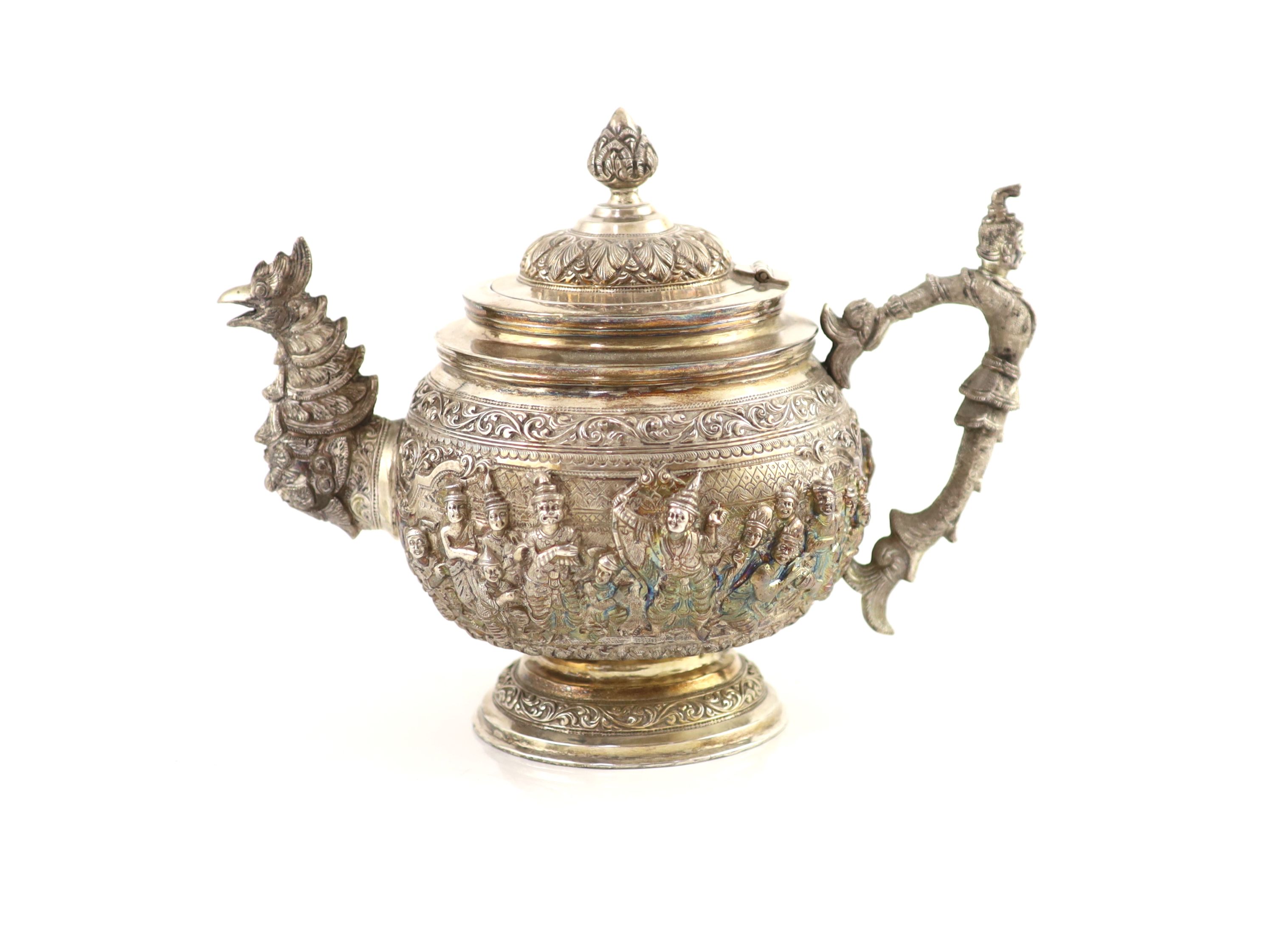 An impressive Burmese Sterling silver (950) three-piece tea service, with tray, cast with figures, teapot with cockerel spout and figural handle
